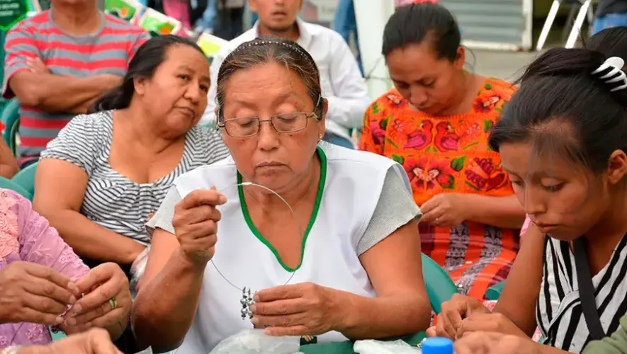 Descripción de la foto para personas con discapacidad visual: Imagen de guatemaltecas de diferentes edades reunidas mientras realizan manualidades. (Crédito: BANRURAL)
