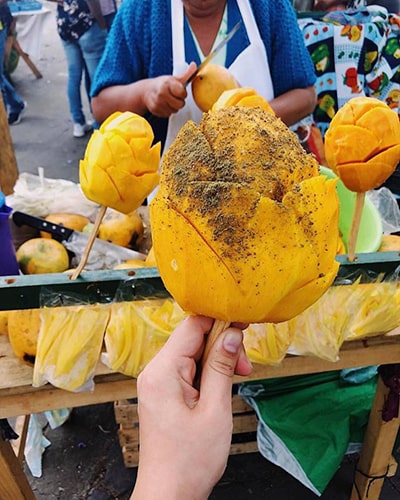 Descripción de foto - Persona sosteniendo una paleta de mango, recién preparada, con pepitoria. - Crédito de foto - Guatemala impresionante