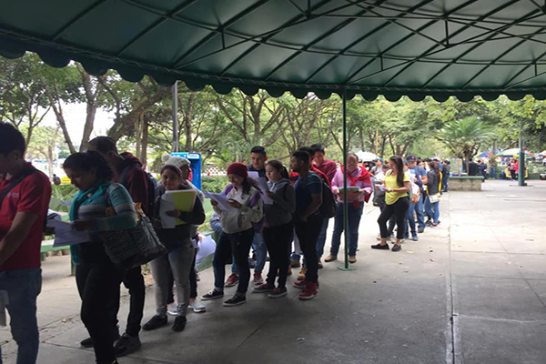 Descripción de la foto - Estudiantes de la USAC haciendo cola y leyendo el boletín del día - Crédito Universidad de San Carlos de Guatemala 2.0