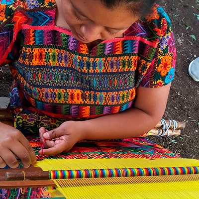 Descripción de la foto - Mujer realizando un tejido típico de colres llamativos como el amarillo, el rojo, el verde y el rosa - crédito de la foto - @guate4you - Instagram