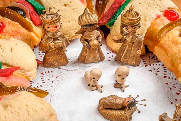 Descripción de la foto - los tres reyes magos en miniatura, en medio de la rosca de reyes, contemplando al niño Jesús en miniatura - Foto Sección Amarilla
