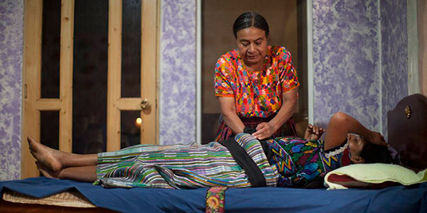 Descripción de foto - Comadrona palpando el estómago de una mujer embarazada. - Crédito de foto - El país