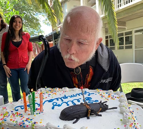 Descripción de foto - Doctor Schuster en el campus de la UVG, soplando unas velas sobre su pastel de cumpleaños - Crédito de foto - Vanesa Granados Barnéond