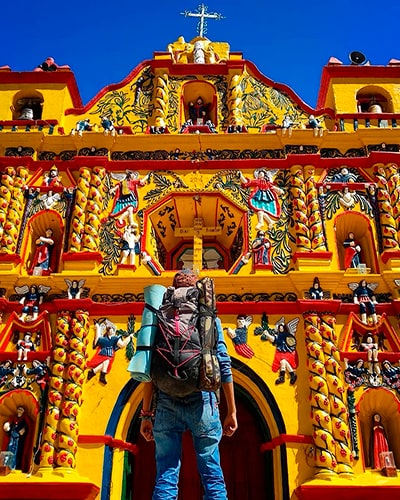 Descripción de foto - Hombre de espaldas, viendo hacia la puerta de la Iglesia de Xecul. - Descripción de foto - @josue.rua- instagram