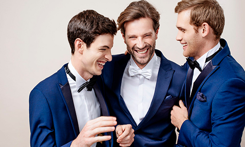 Descripción de foto - Hombres, de diferentes edades, vestidos de traje riendo juntos. - Crédito de foto - Saúl E. Méndez