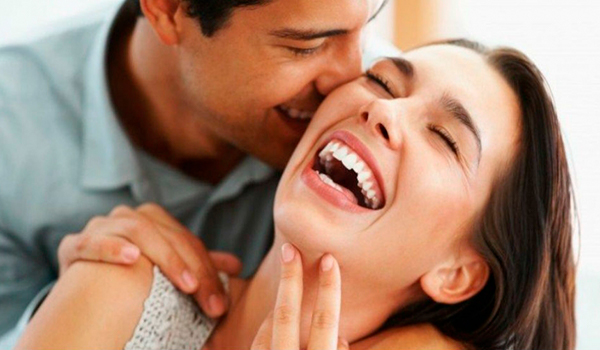 Descripción de foto - Hombres hablándole al oído a una mujer, mientras ella ríe. - Crédito de foto - Seguimiento . com