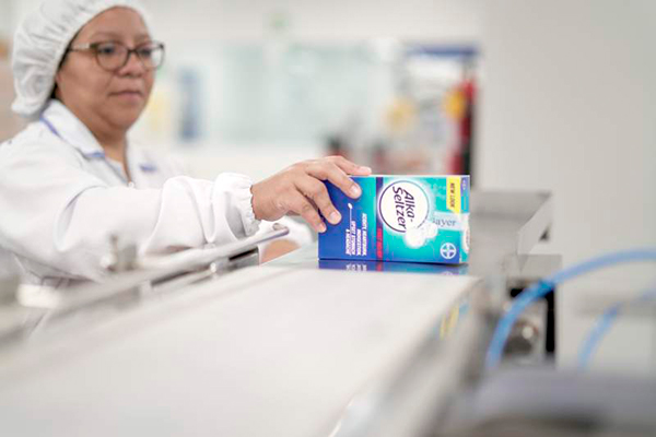 Descripción de foto - Mujer en el laboratorio sosteniendo una caja de Alka Seltzer. - Crédito de foto - Estrategia & Negocios