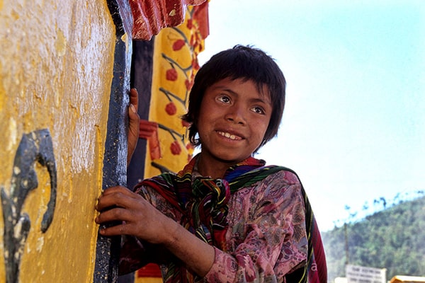 Descripción de foto - Niño vistiendo colorido traje típico en frente de la Iglesia de San Andrés Xecul Guatemala. - Crédito de foto - RFoxPhotography