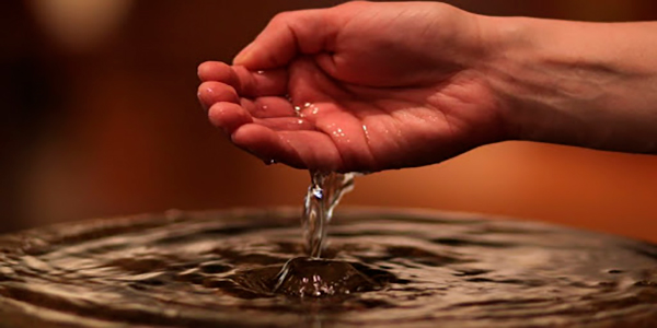 Descripción de foto - mano de hombre tomando agua de una pila previamente bendecida. - Crédito de foto - Upsocl