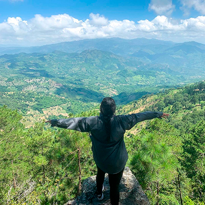 Descripción de foto - Mujer parada sobre una roca, alzando los brazos, con vista a la naturaleza del municipio de Ipala. - Crédito de foto - kareniskarma - instagram
