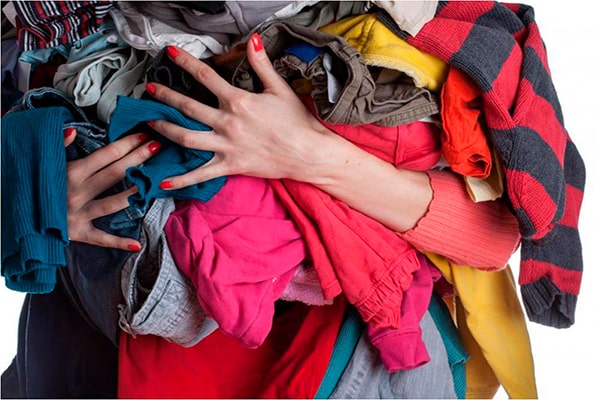 Descripción de foto - mujer sosteniendo muchas prendas de ropa en sus brazos. - Crédito de foto - Significado de los sueños