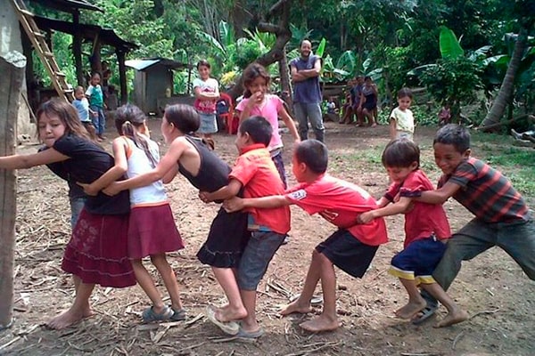 Descripción de foto - niños en una aldea jugando arranca cebollas abrazados a un palo de madera. - Crédito de foto - Noé Lemus