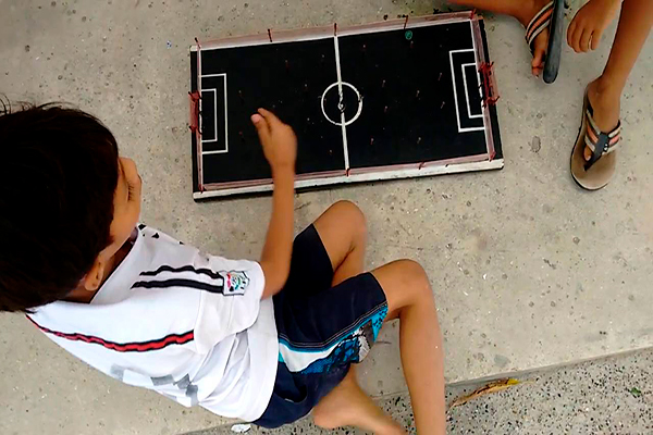 Descripción de foto - niños jugando con el futillo de tabla en el piso. - Crédito de foto - Willy Willy
