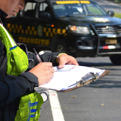 Descripción de la foto para personas con discapacidad visual - Agende de Emetra realizando una multa.- Crédito de foto - Departamento de Tránsito de la Policía Municipal