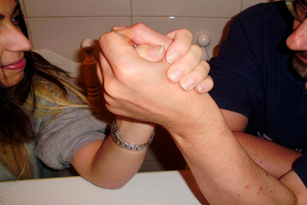Descripción de la foto para personas con discapacidad visual - Hombre y mujer jugando pulso de manos cara a cara.- Crédito de foto - Psygan