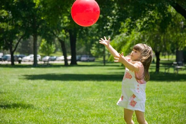 Descripción de la foto para personas con discapacidad visual - Niña atrapando una pelota en el aire.- Crédito de foto - Baby Sparks