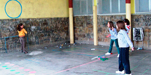 Descripción de la foto para personas con discapacidad visual - Niñas detenidas mientras otra las observa pegada por la pared. - Crédito de foto - AF2Toral