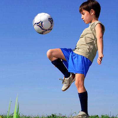 Descripción de la foto para personas con discapacidad visual - Niño haciendo fintas con la pierna mientras rebota la pelota.- Crédito de foto - Guía infantil
