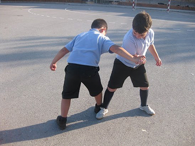 Descripción de la foto para personas con discapacidad visual - Niños jugando pulso de pies y manos en una cancha. - Crédito de foto - Juegos de tiempo libre
