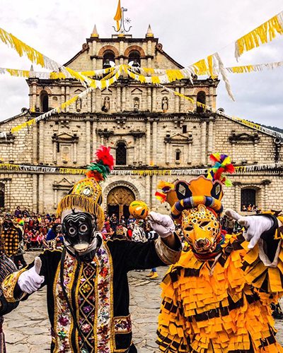 Descripción de la foto para personas con discapacidad visual - Personas vestidas para el baile de los negritos frente a la iglesia de Panajachel. - Crédito de foto - Eduardo Rodríguez