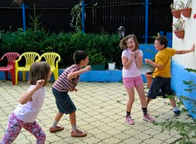 Descripción de la foto para personas con discapacidad visual- niños jugando 1, 2, 3 cruz roja, y otro niño tocando la pared - Crédito de foto - Educación Física Bilingue en Primaria